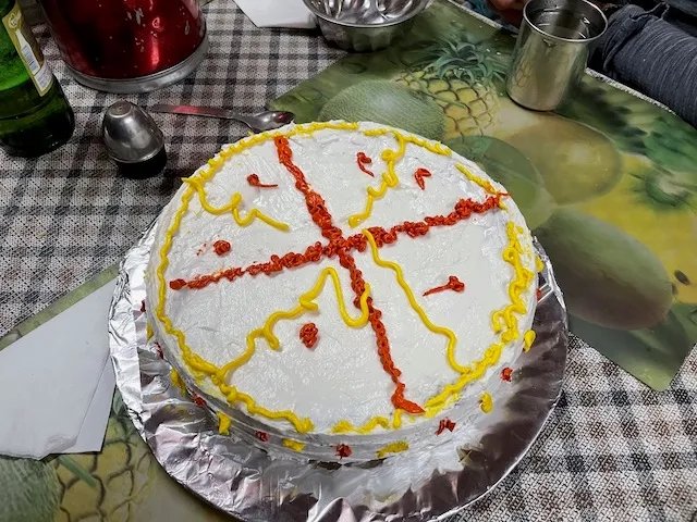 a large cake with shite icing and red and yellow decoration