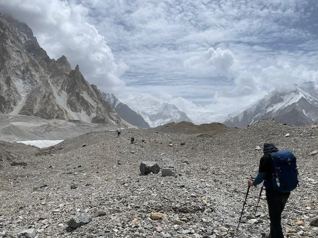 a trekker walking on a large glacier with mountain peaks in the distance