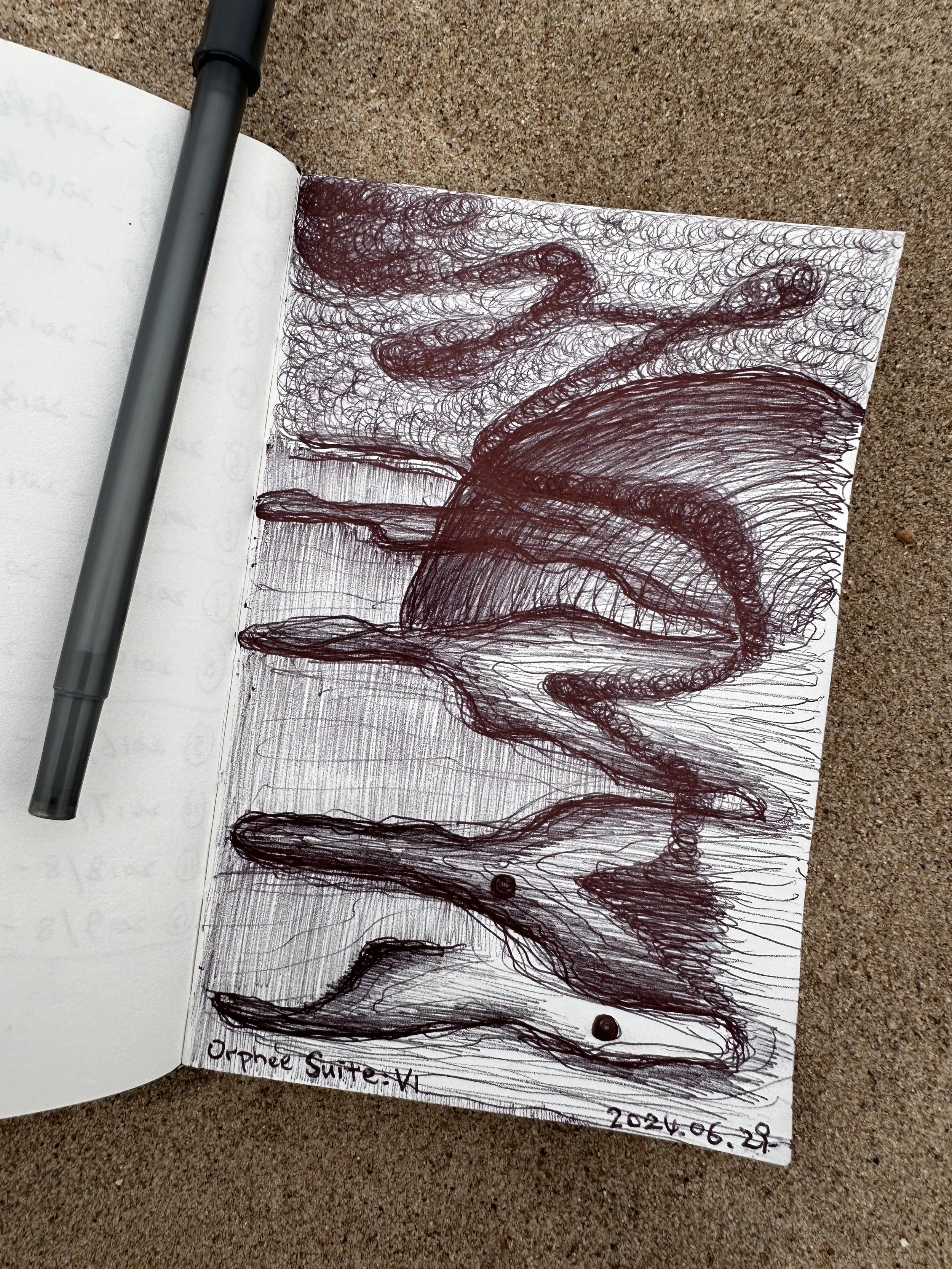 A sketch of a woman with long hair sitting on the ground with her legs crossed, drawn with red ink on a white sheet of paper. The drawing is made using swirling, overlapping lines. The paper is in an open notebook, and a gray marker is placed on the 