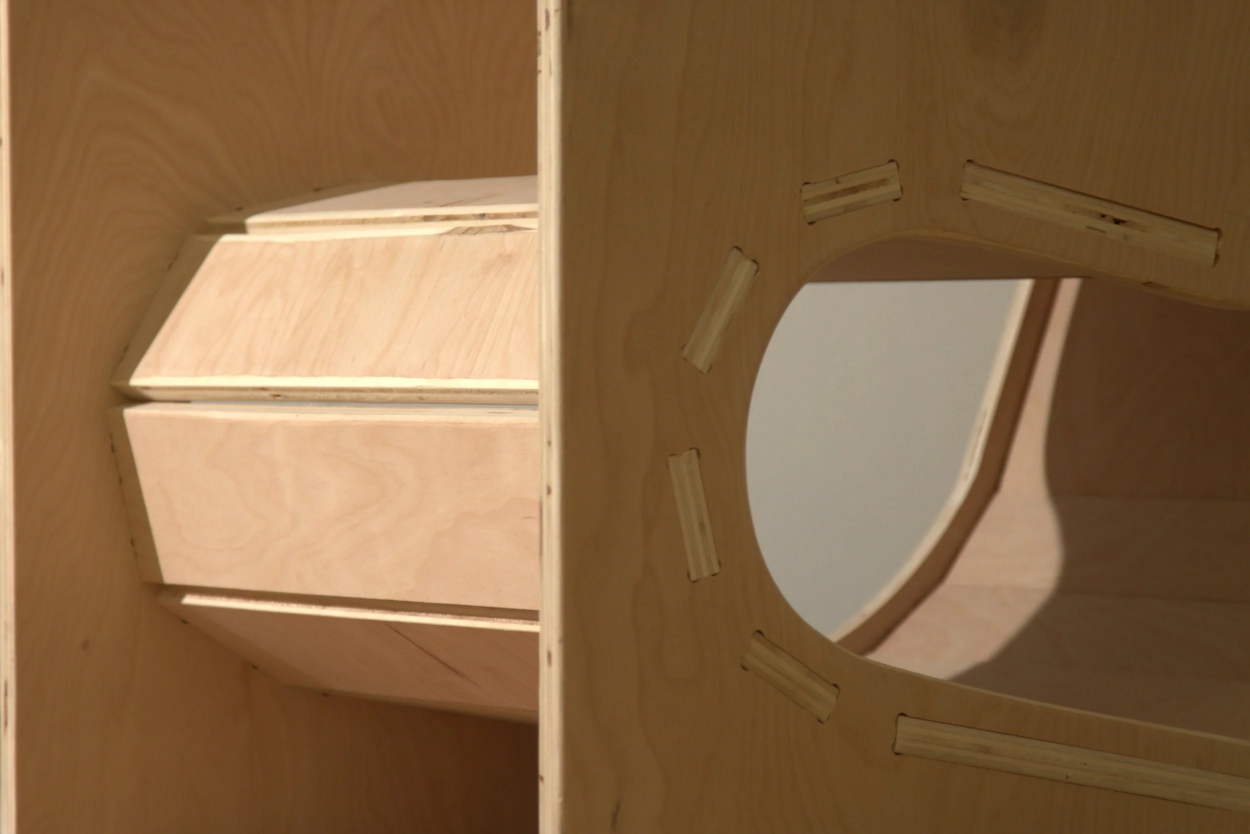 Close-up of a wooden furniture piece with a cut-out section, showing its interior structure and slots for assembly.