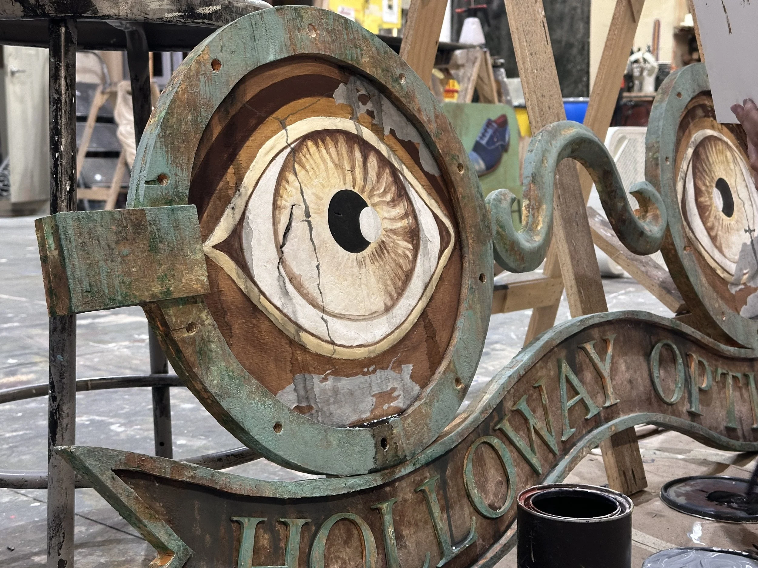 Painted wooden signs with eye illustrations at an art market stall.