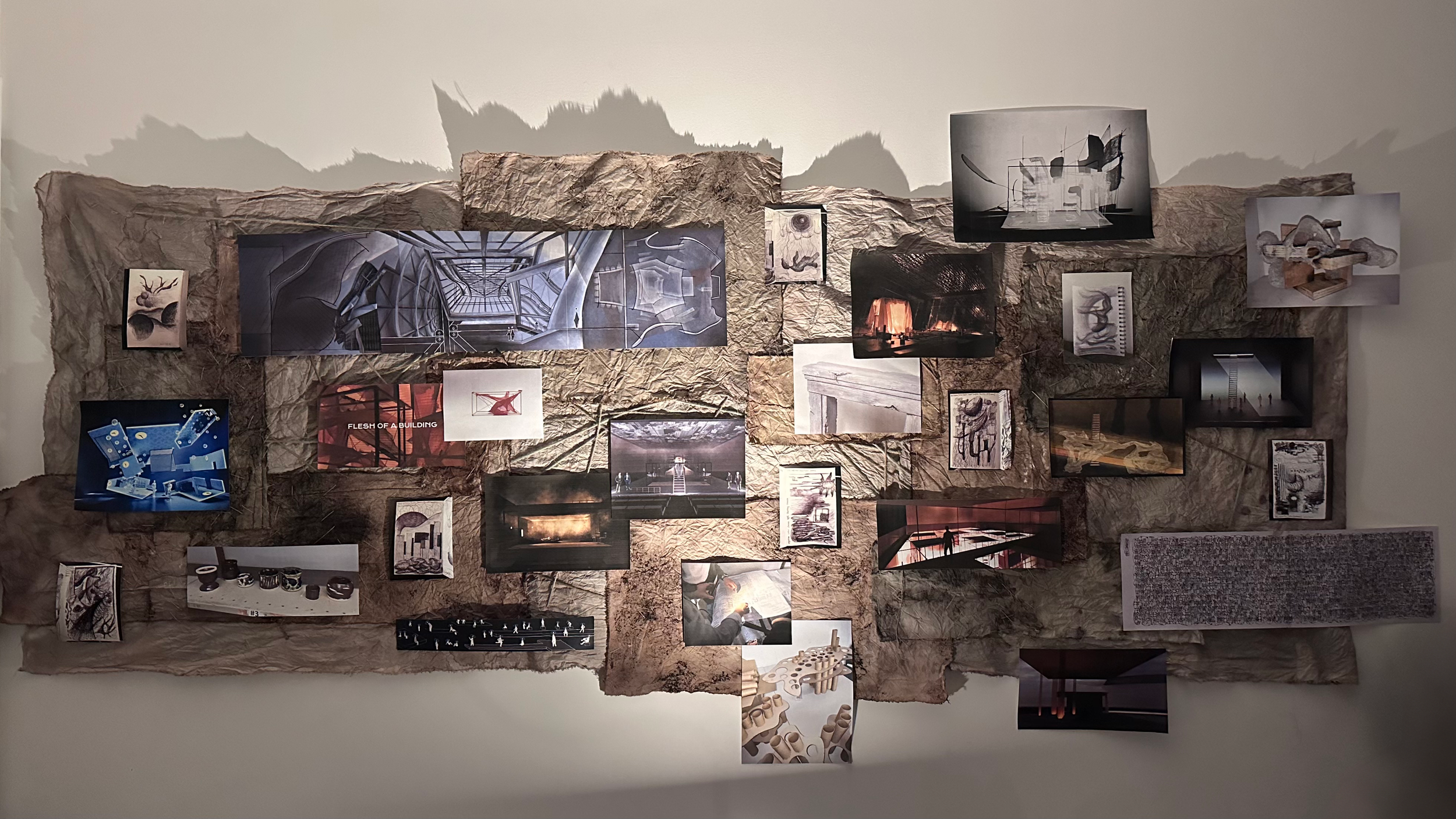 A collage on a textured wall featuring various artworks, photographs, sketches, and objects, including architectural designs, artistic portraits, and creative concept images.