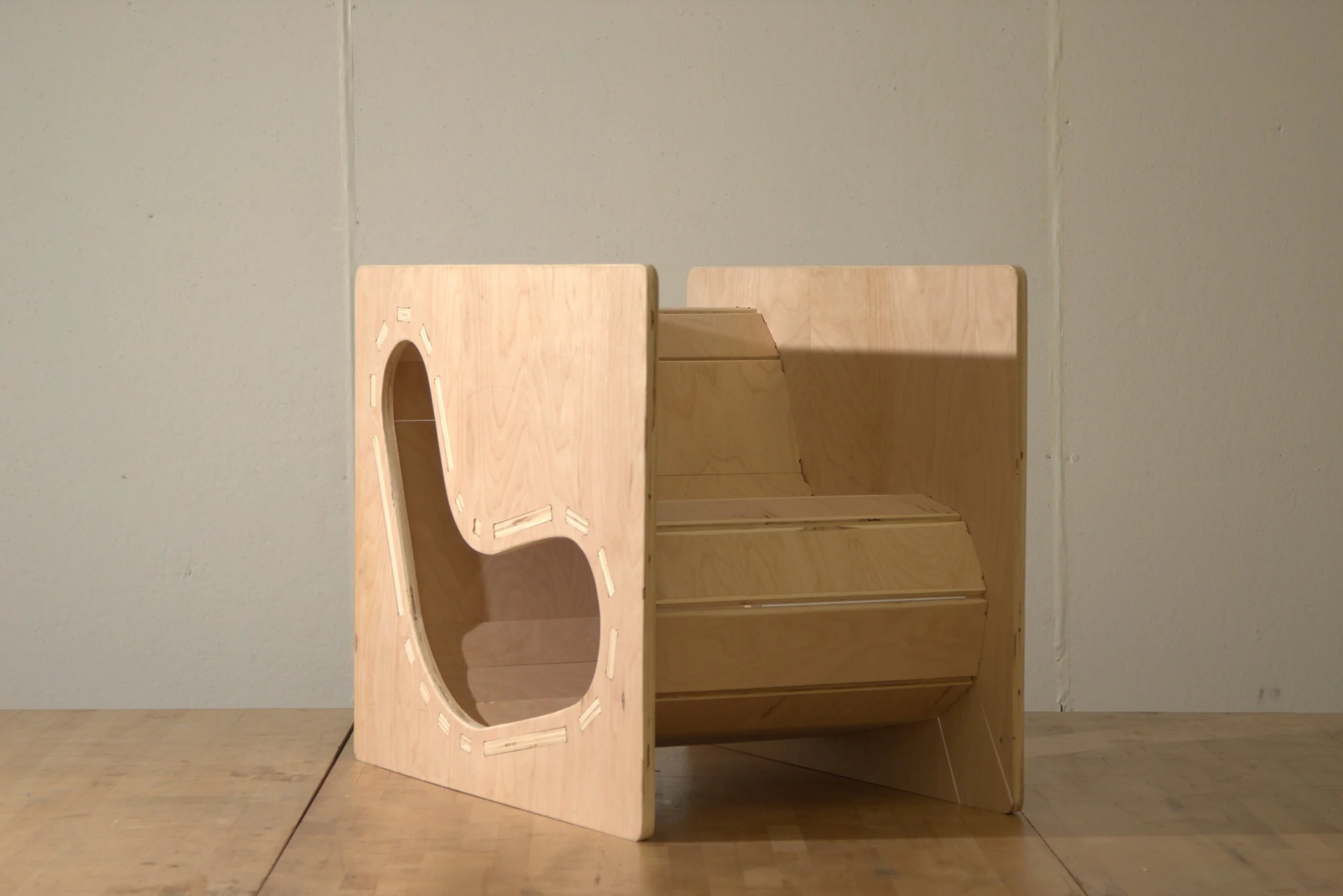 Unfinished wooden furniture on a wooden floor against a plain wall.