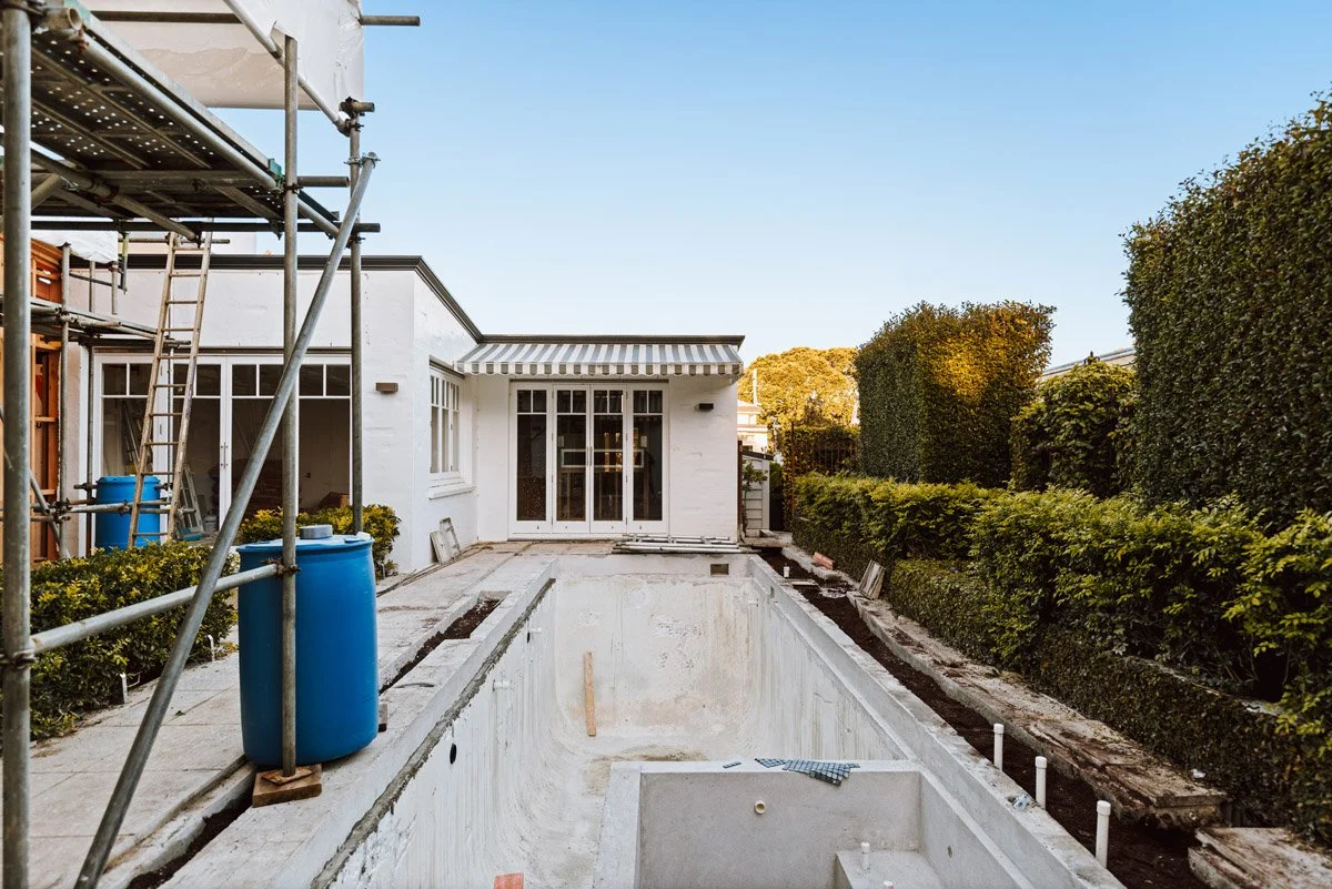 Concrete swimming pool construction underway alongside a luxury home renovation project in Auckland by Coast & Country Homes.