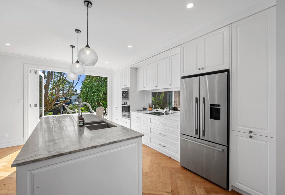 Custom white kitchen with stone benchtops and large island completed as part of a Devonport villa renovation.
