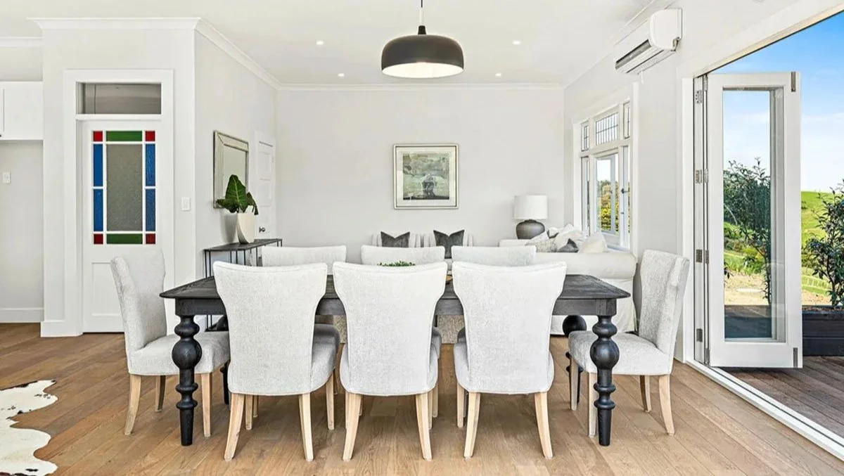Dining space inside restored Matakana country villa with stained glass door details, timber flooring and indoor outdoor flow.
