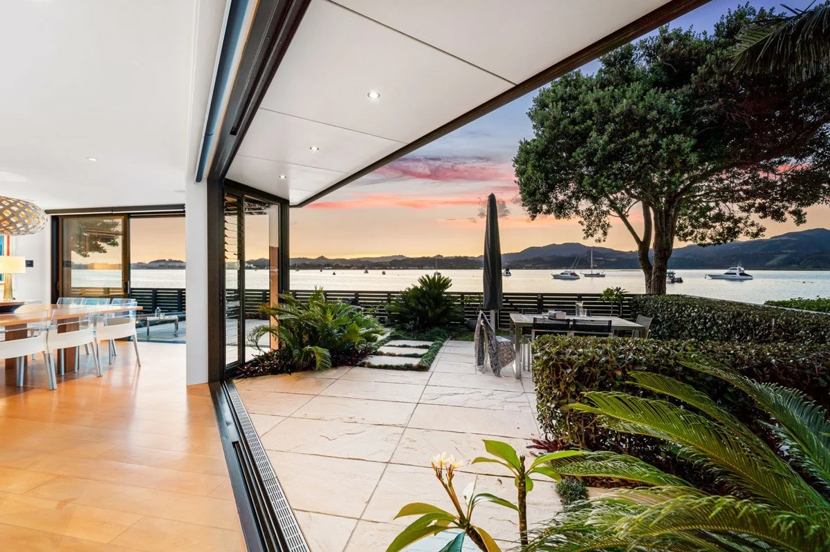 Outdoor entertaining area overlooking the water with landscaped gardens and seamless connection to the interior living spaces.