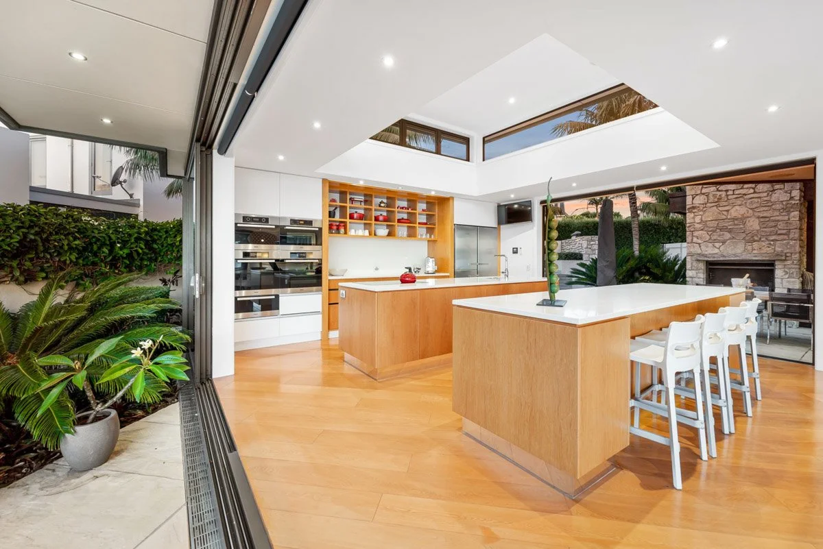 Open-plan kitchen and living area with timber finishes, skylights and seamless indoor outdoor flow in an Omaha waterfront residence.