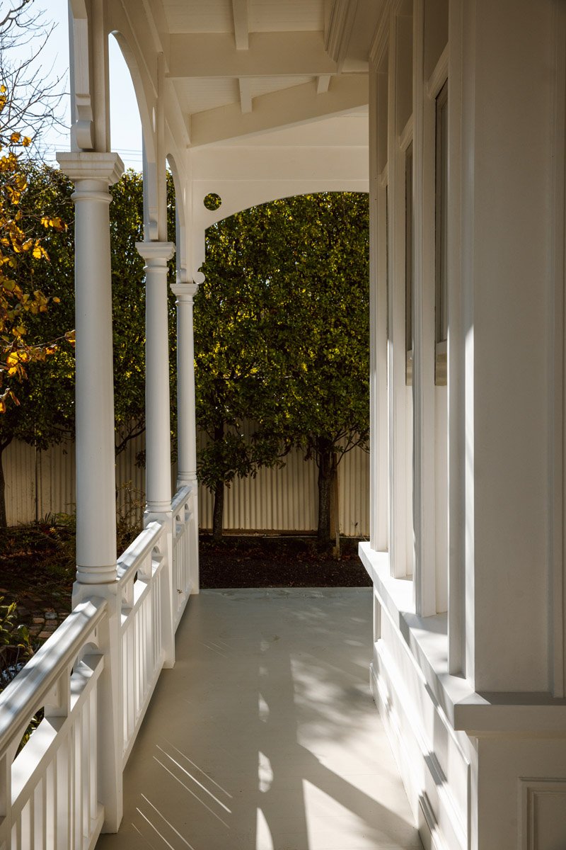 Covered verandah with restored timber columns, balustrades and heritage detailing at a renovated character home in Narrow Neck, Auckland.