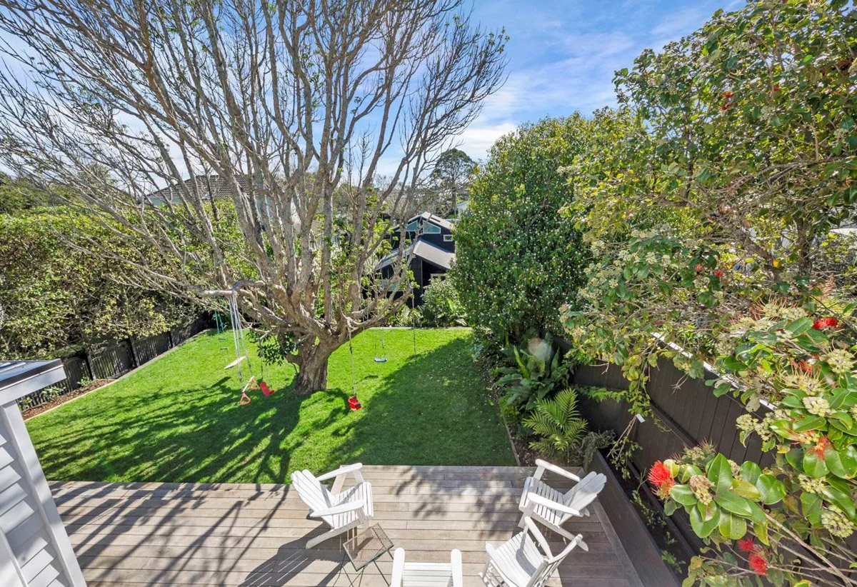 Landscaped backyard with lawn, mature tree and outdoor entertaining spaces at renovated Devonport villa.