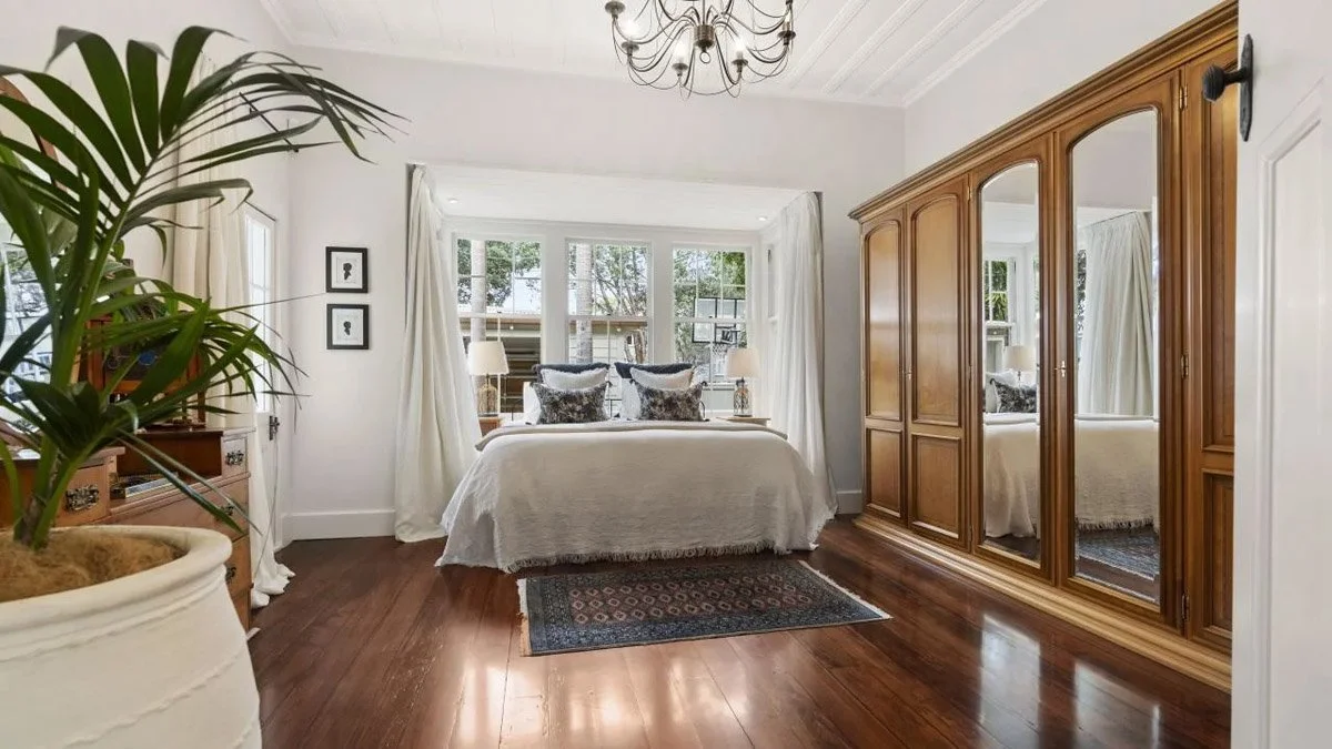 Spacious master bedroom with polished timber flooring and restored character detailing
