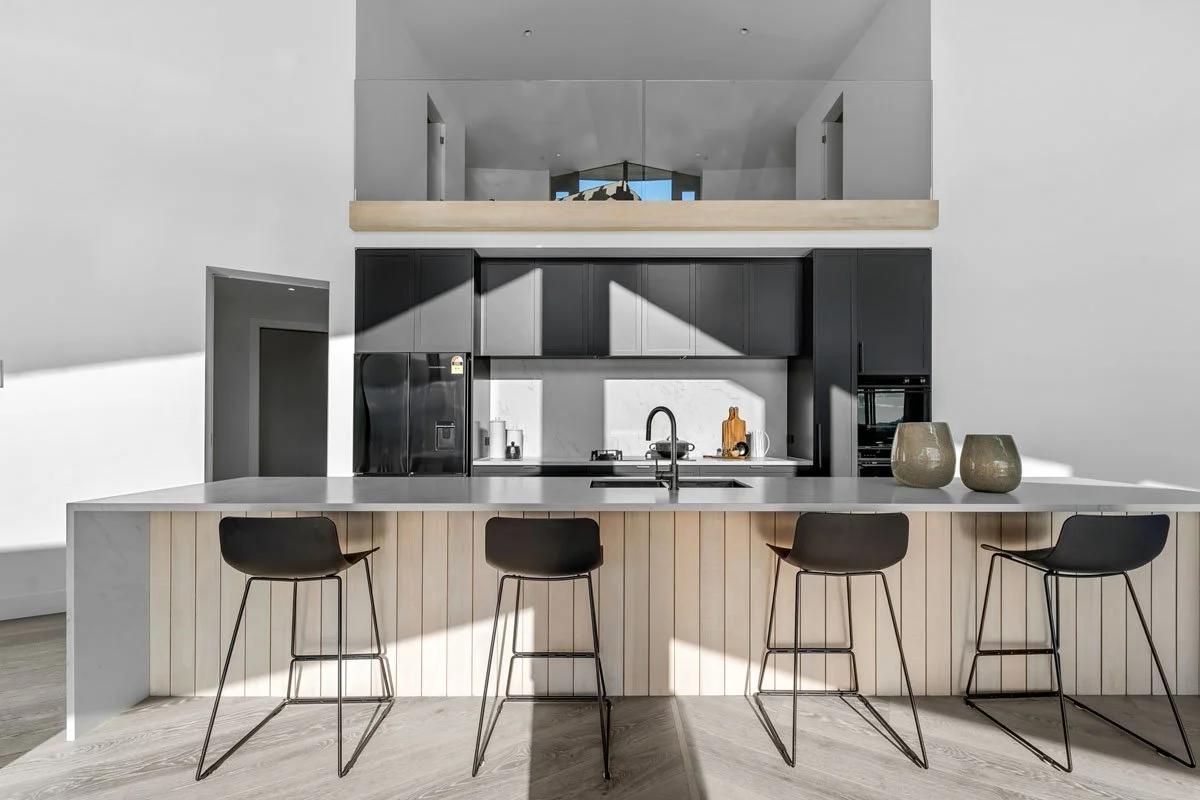 Architectural kitchen with stone island and timber detailing in Matakana