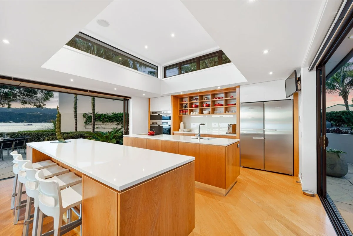 Architectural kitchen opening to a sheltered courtyard and outdoor entertaining area in an Omaha waterfront home.