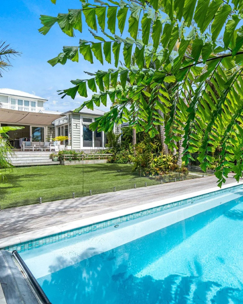 Swimming pool and outdoor entertaining area surrounded by tropical landscaping at a renovated Stanley Point home.