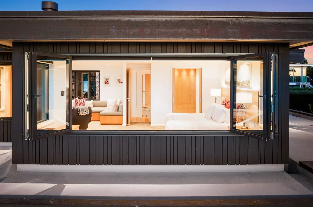 Waterfront bedroom suite with large opening windows, built-in seating and views across the Omaha harbour.