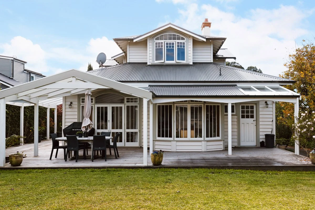 Rear elevation of a renovated character home in Hauraki featuring a covered outdoor entertaining area, timber deck and heritage architectural detailing.