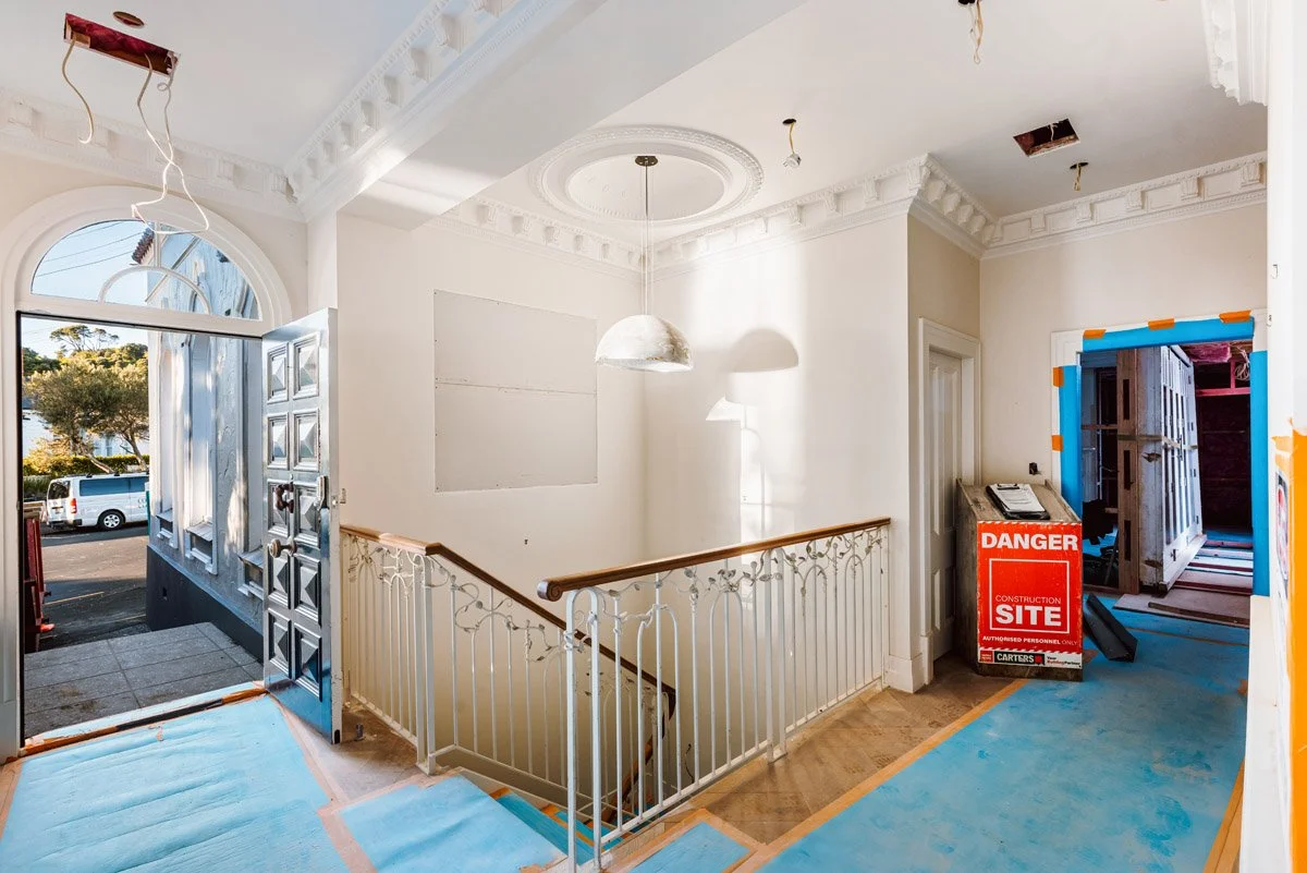 Restored heritage entrance hallway with ornate ceiling details and decorative balustrade during a high-end Auckland villa renovation by Coast & Country Homes.
