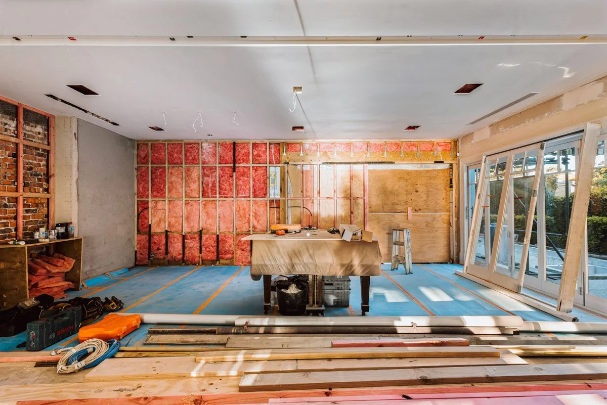 Open-plan living area under construction during a luxury home renovation by Coast & Country Homes in Auckland, featuring structural framing, insulation and new joinery installation.