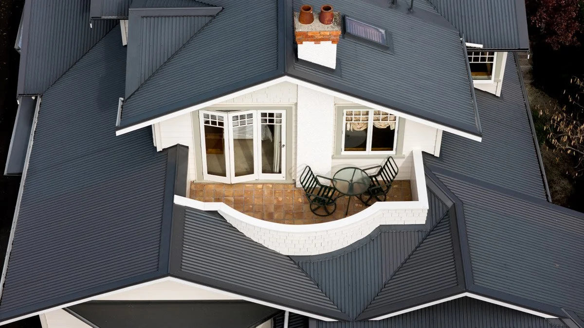 Drone view showcasing the upper-level balcony, restored rooflines and architectural detailing of a character home renovation in Hauraki.