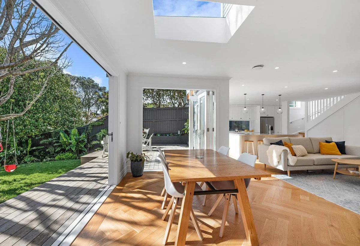 Dining area with skylight and seamless indoor outdoor flow created during major Devonport villa renovation.