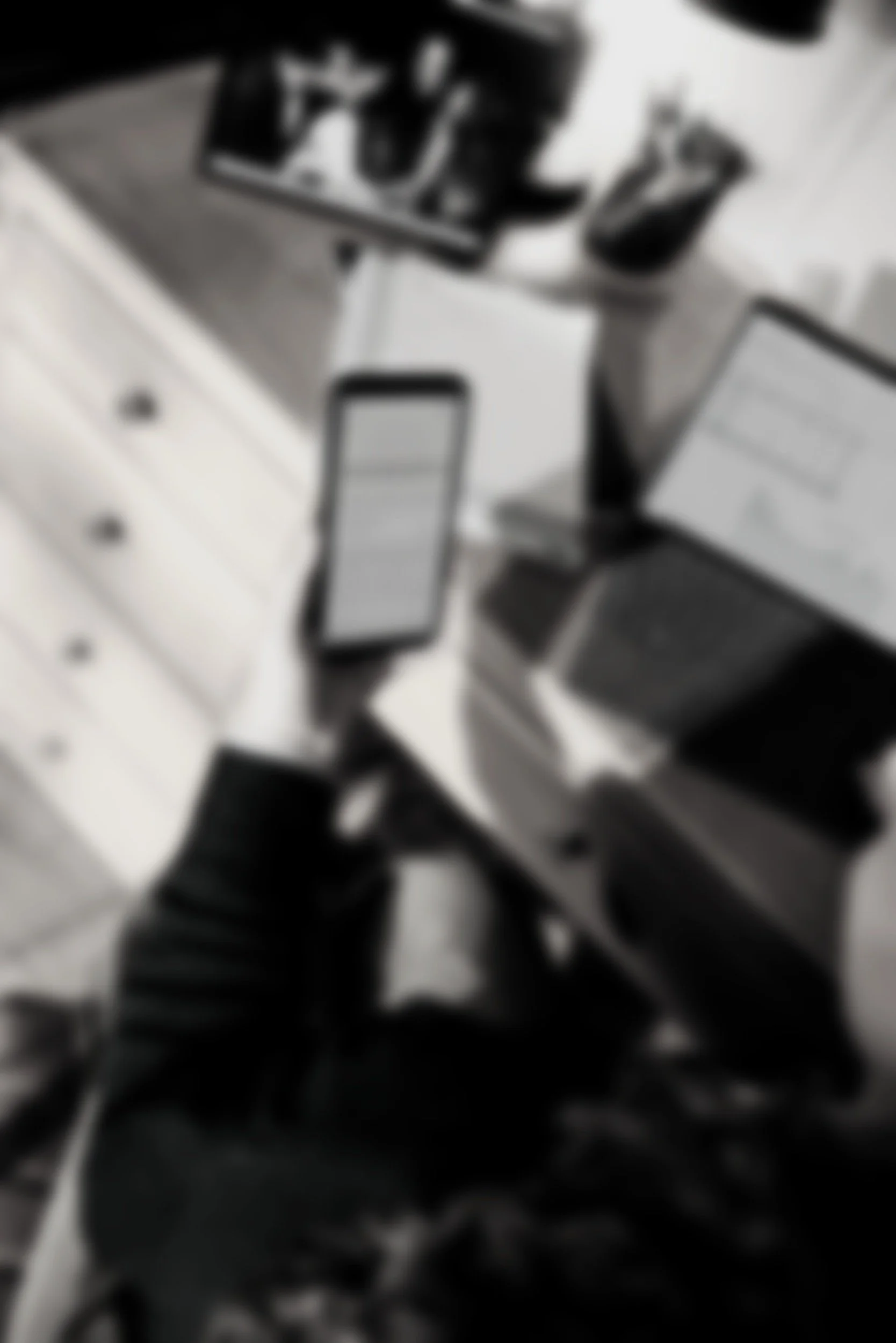 A blurry black and white photo of a laboratory equipment and a smartphone on a tray or surface.