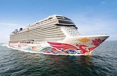 Large cruise ship sailing on the ocean with colorful artwork on its hull.