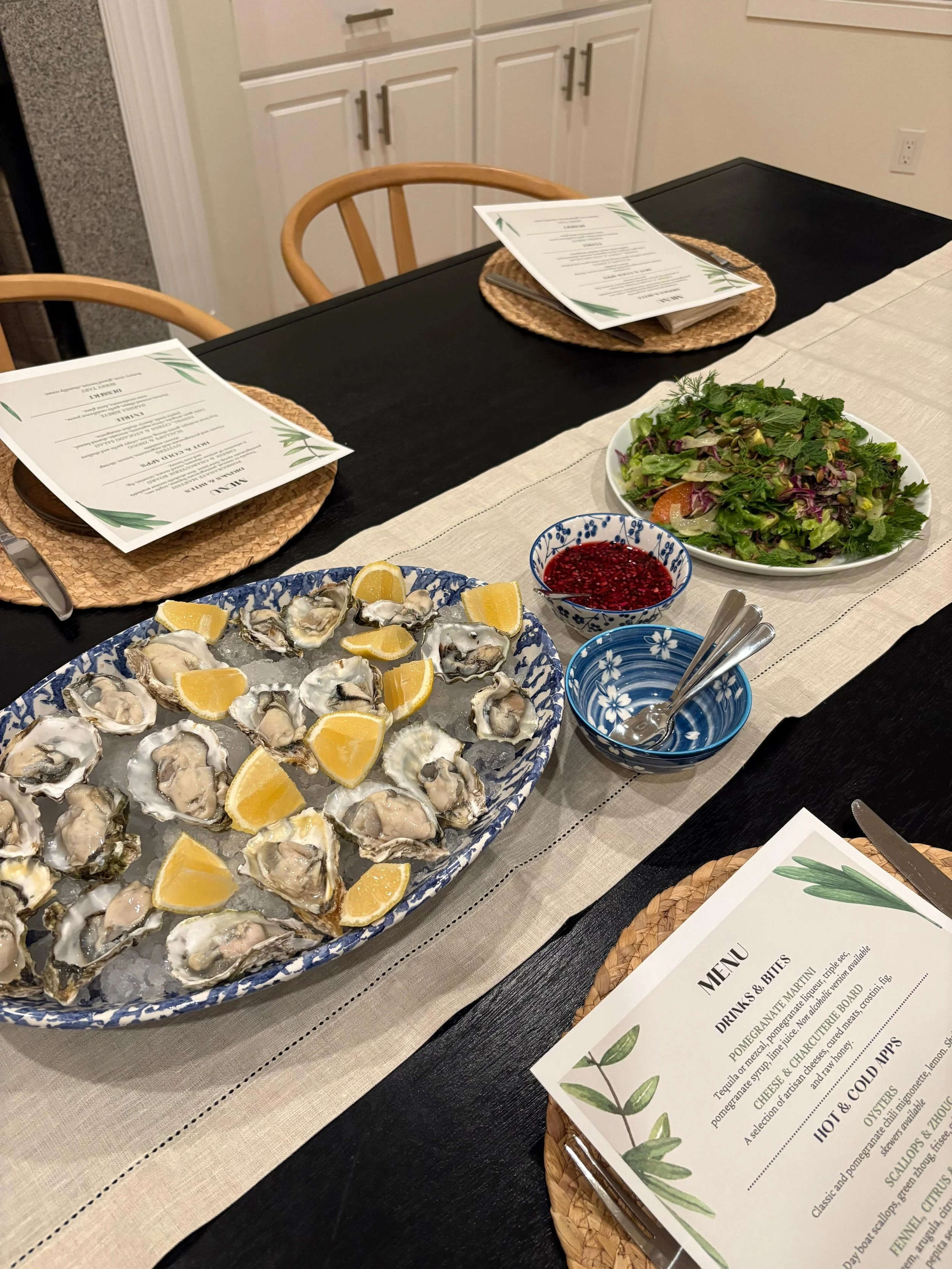 Table with oysters and a salad at a dinner party event.
