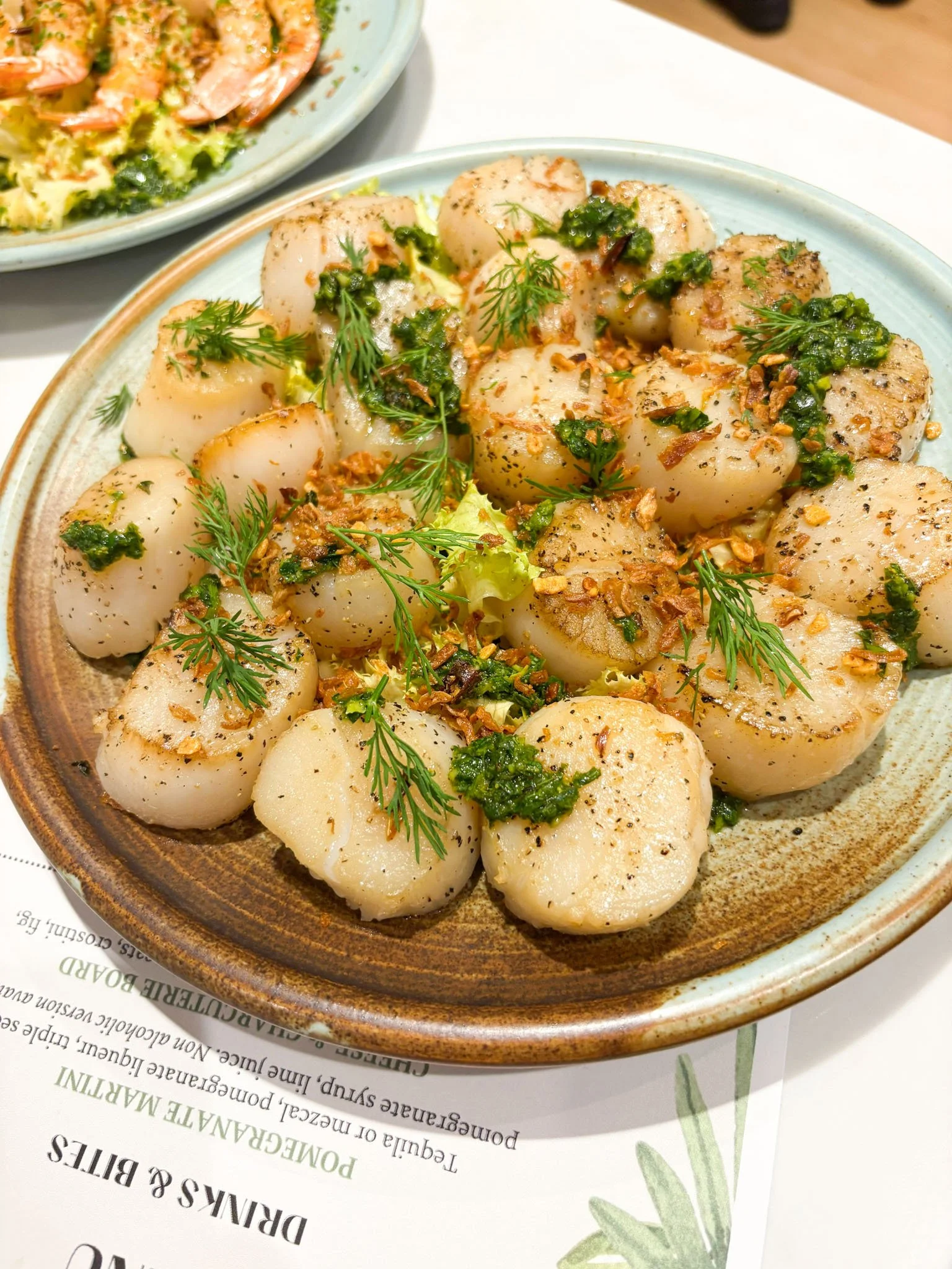 Scallops with herbs on top served on a table.