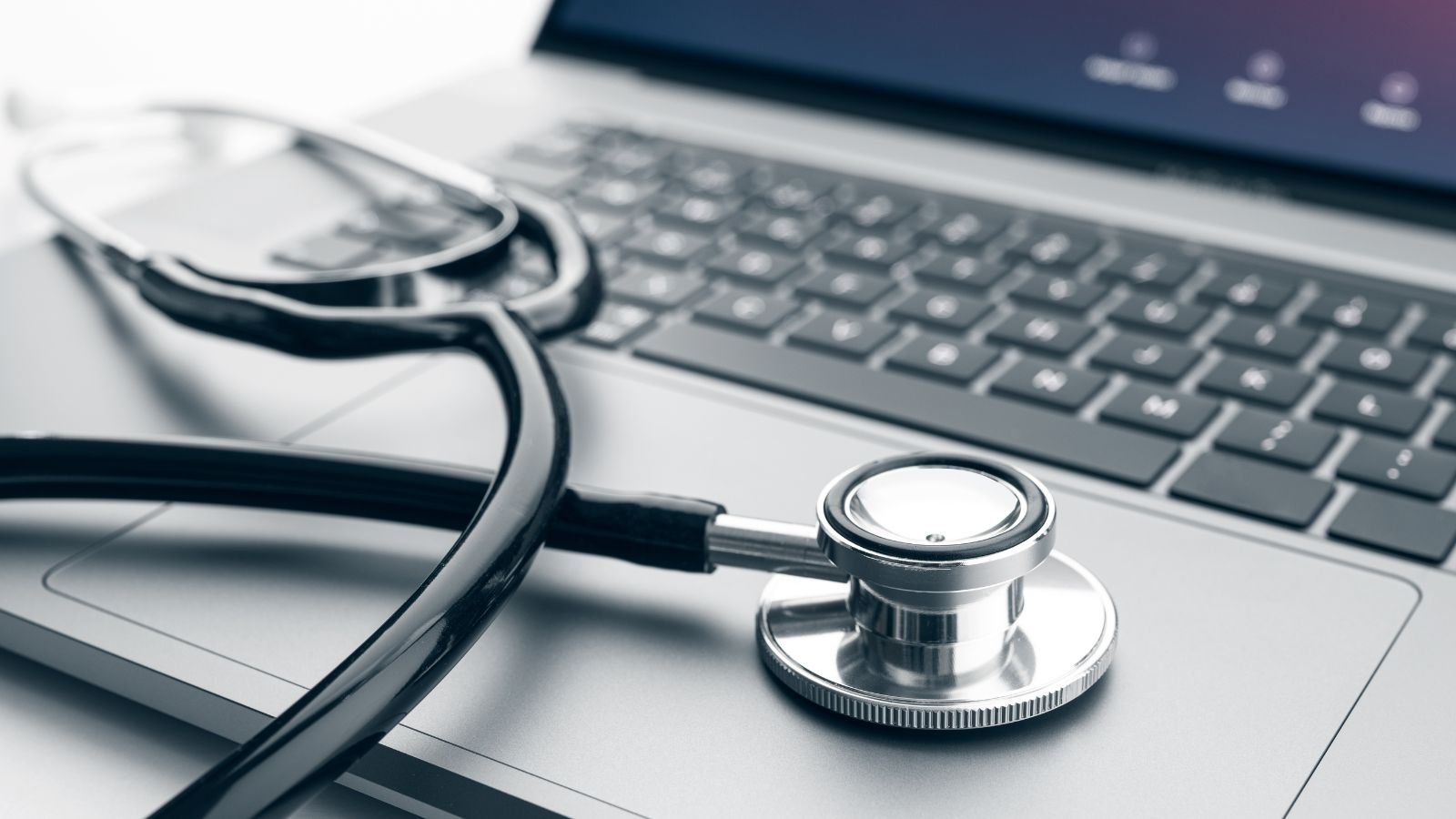 A stethoscope and a laptop on a desk, indicating a medical or healthcare setting.