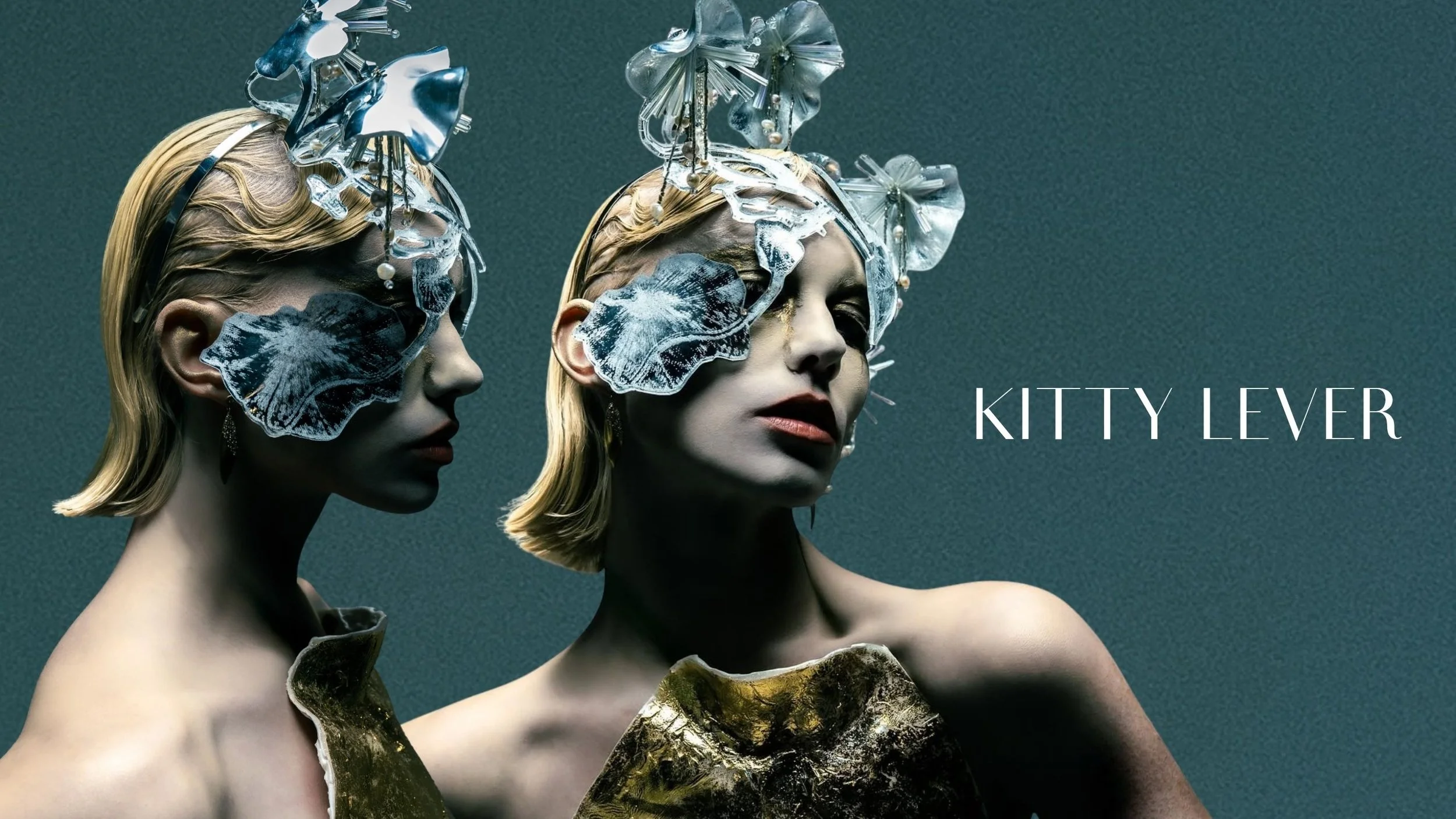 Two mannequins with elaborate headpieces made of transparent, metallic, and pearl-like ornaments, and gold accents. They have short blonde hair and smooth skin. The background is dark and textured. The text 'KITTY LEVER' appears in white in the botto