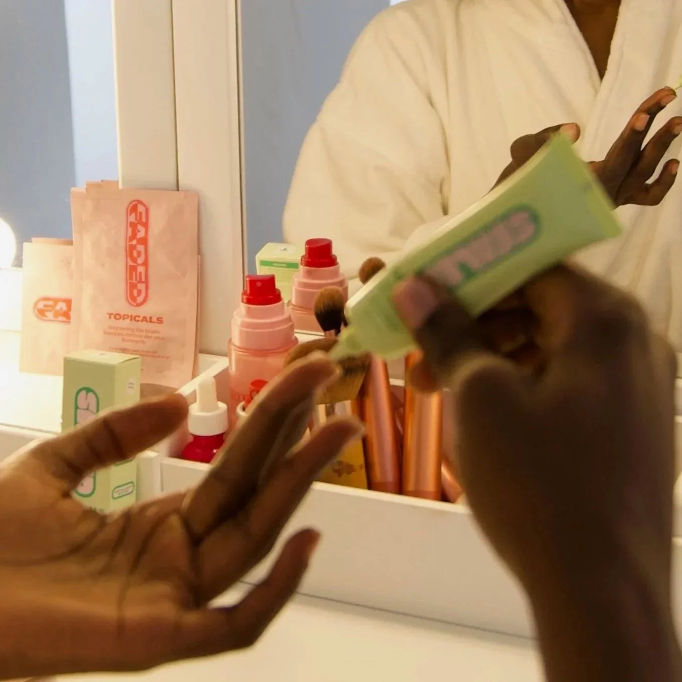 Someone applying skincare products in front of a mirror with various skincare items on the counter.
