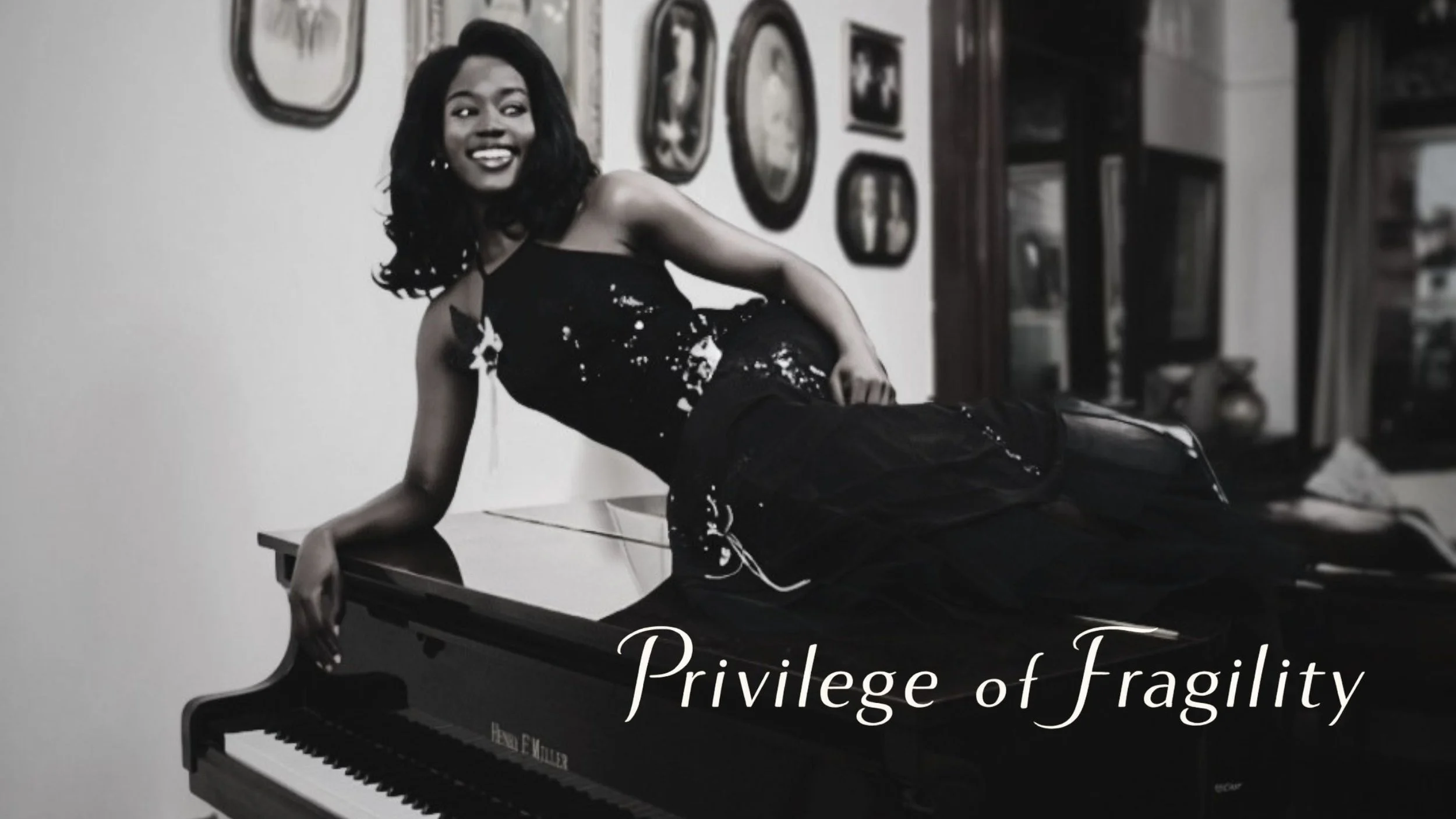 Black-and-white photo of a woman sitting on a table in front of a piano, smiling. Art gallery wall with framed pictures in the background. Text overlay says 'Privilege of Fragility'.