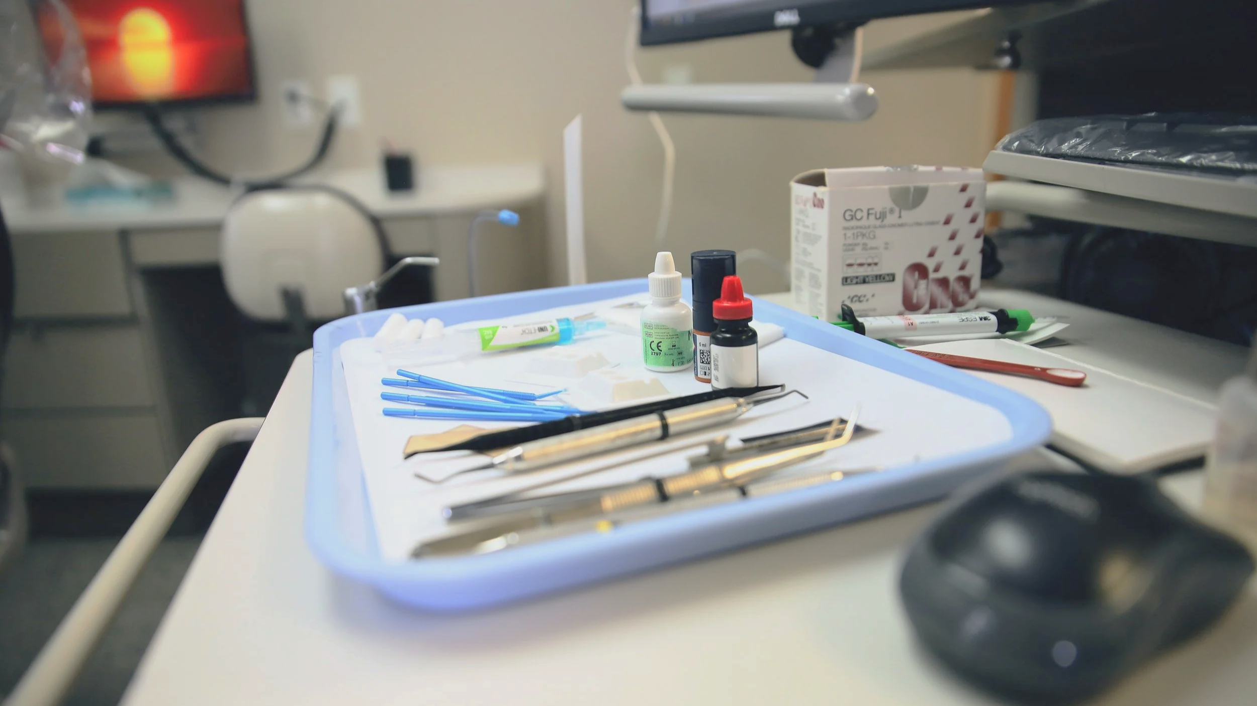 Medical tools and supplies on a tray, including syringes, bottles, and surgical instruments, in a clinical setting.