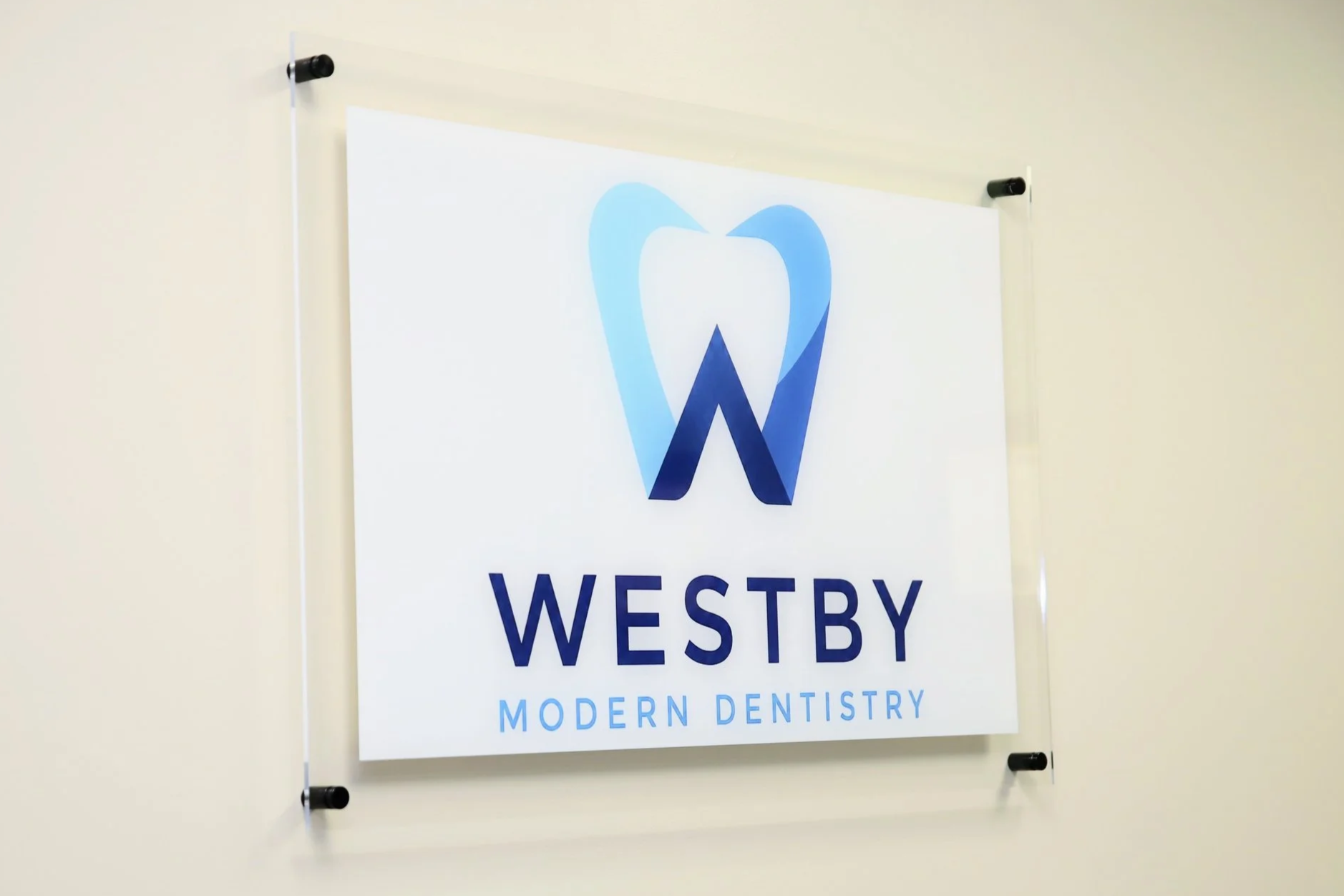 Sign for Westby Modern Dentistry, featuring a blue tooth-shaped logo and blue text.