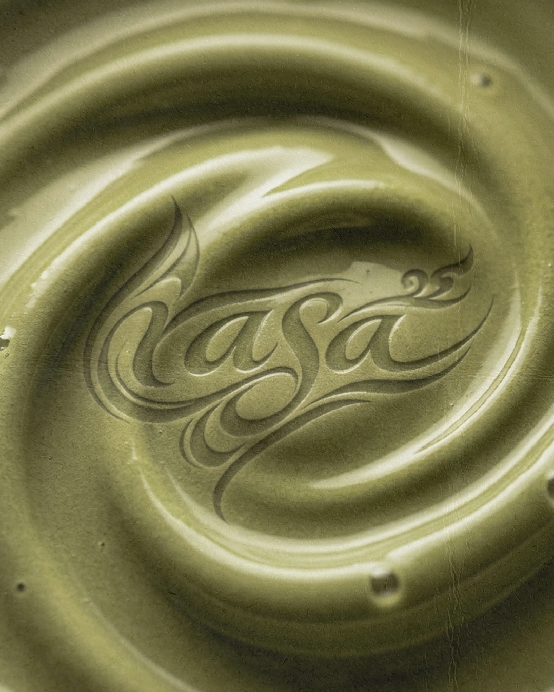 Close-up of a greenish metallic surface with the word 'Nasa' engraved in decorative cursive.