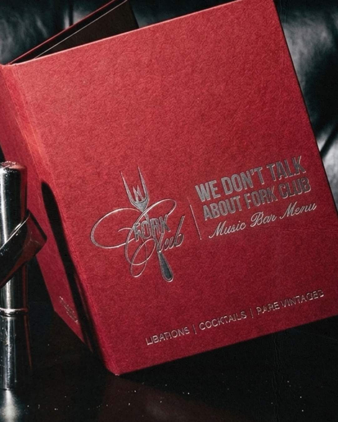 Red menu titled 'We Don't Talk About Fork Club' with words 'Libations, Cocktails, Pies/Vintage' at the bottom, and an illustration of a fork and a knife crossed over the word 'Fork Club'