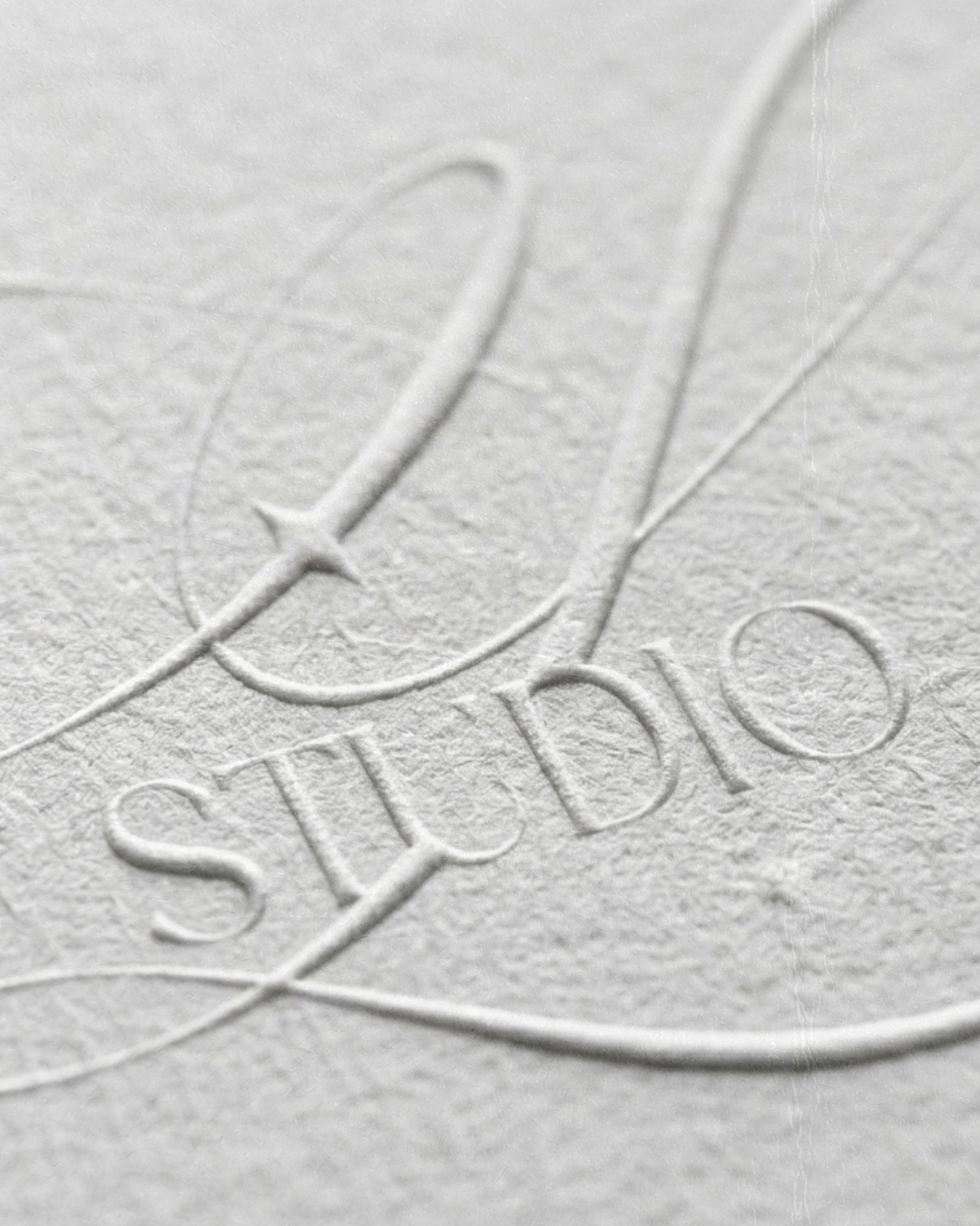 Close-up of the embossed word 'Studios' on textured white paper.