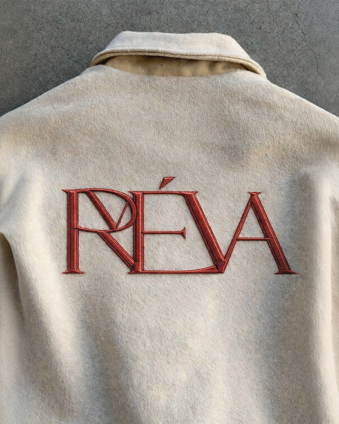 A beige coat with a large embroidered red logo reading 'Révo' on the back.