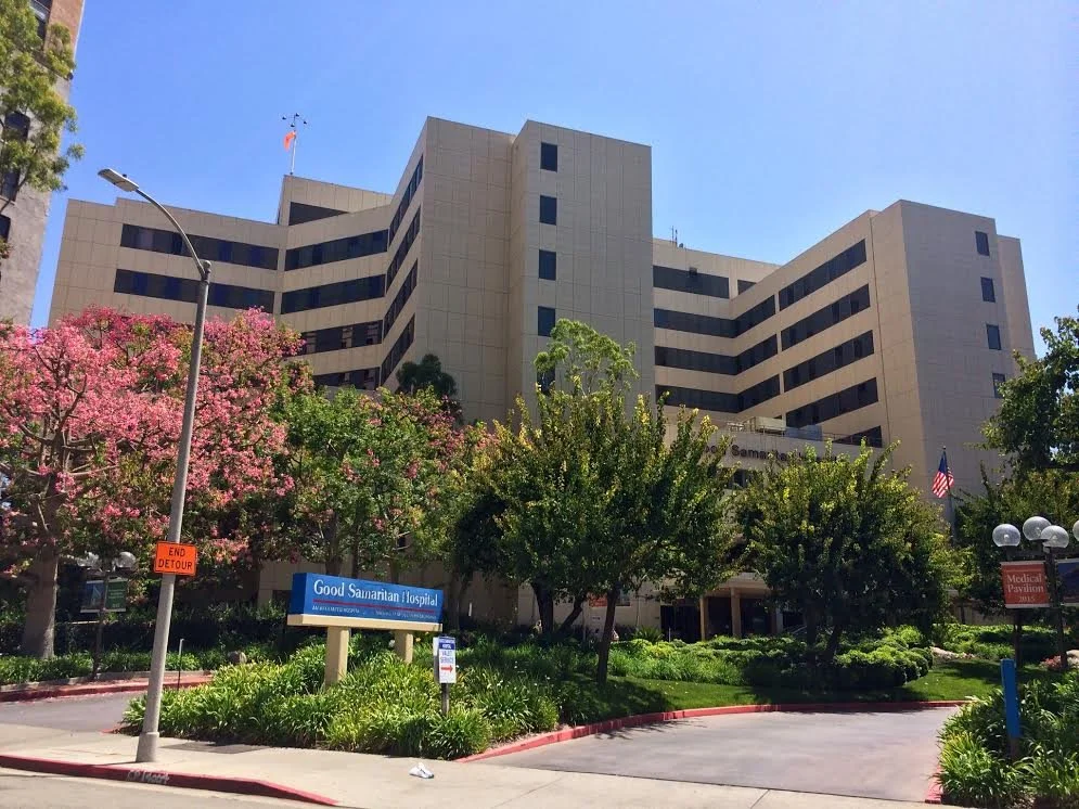 Exterior view of Good Samaritan Hospital with trees and landscaping in front on a clear sunny day.