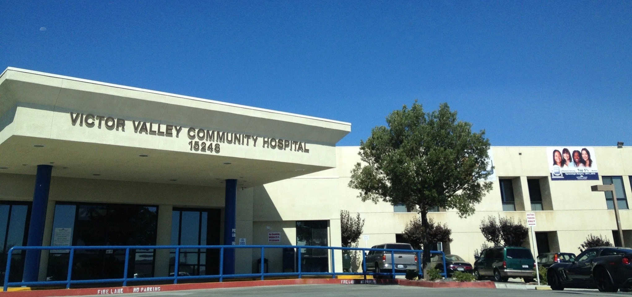 Exterior view of Victor Valley Community Hospital with parking lot, trees, and a blue sky.