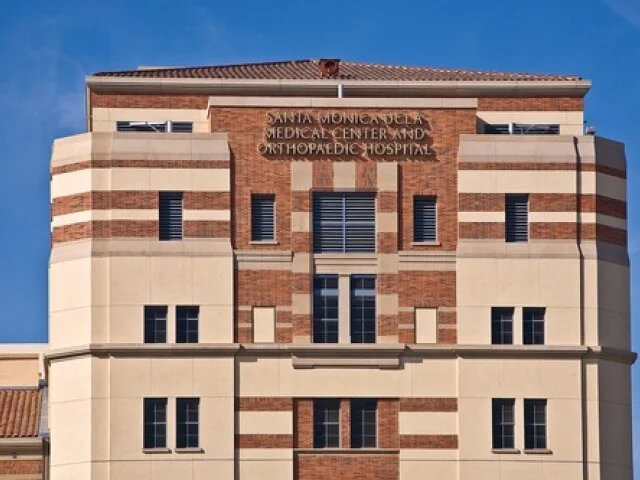 Front view of Santa Monica Delta Medical Center and Orthopedic Hospital building with brick and beige exterior, multiple windows, and blue sky backdrop.