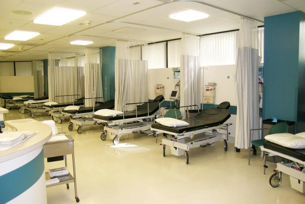 Hospital empty patient beds with curtains in a medical room.