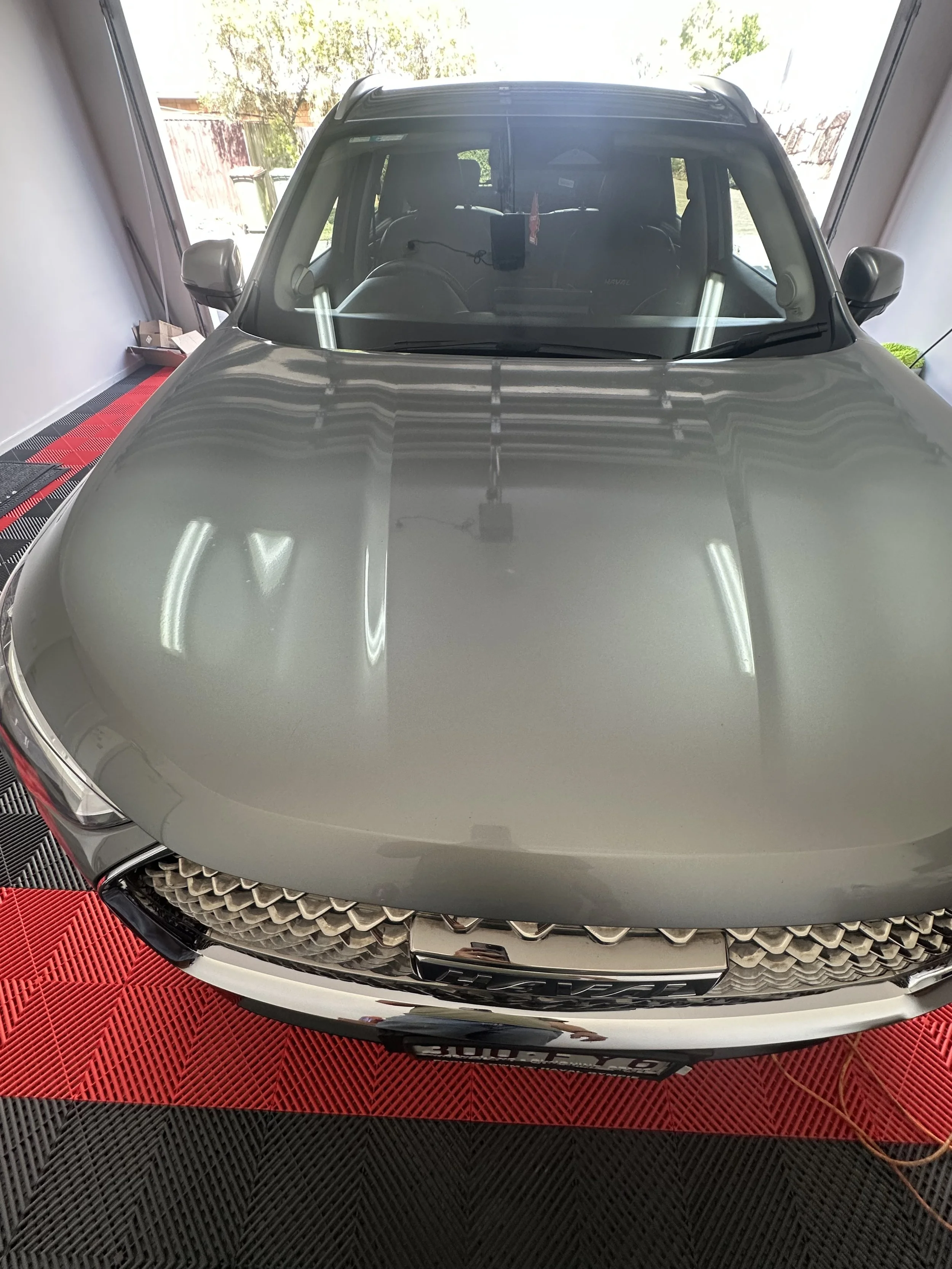 Silver car parked inside a garage with a red and black floormat.