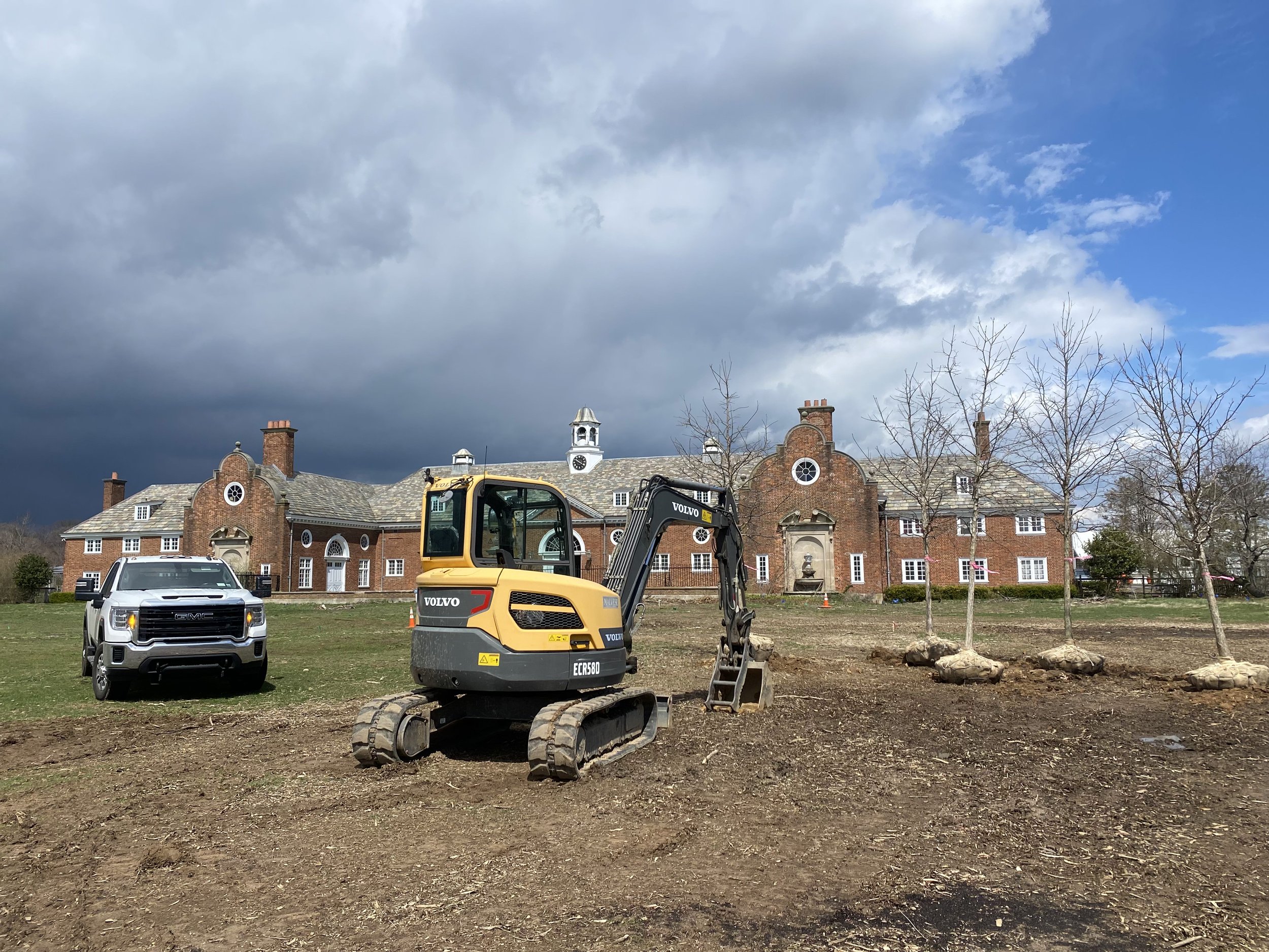 Yellow construction vehicle, likely a wheel loader, parked on a construction site with apartment buildings in the background.