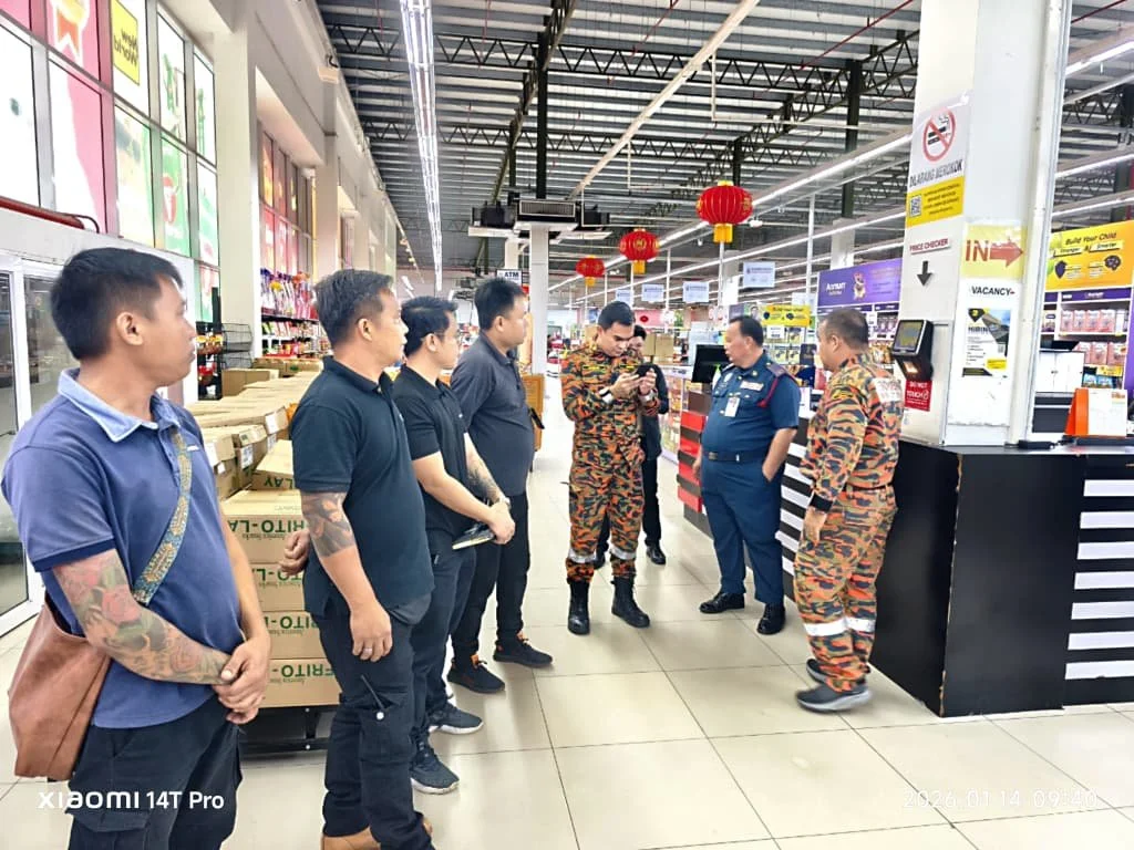 Group of men, including some in uniforms, standing and talking inside a store, with red lantern decorations hanging from the ceiling.