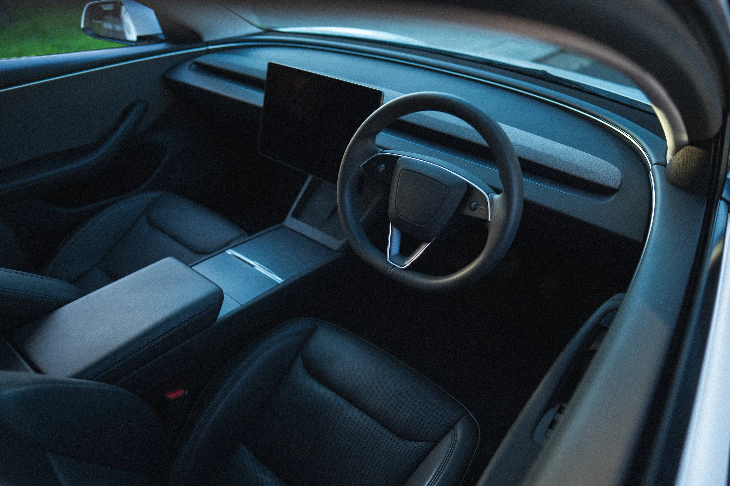 Interior of a modern car with a digital dashboard, steering wheel, and a central touchscreen display.