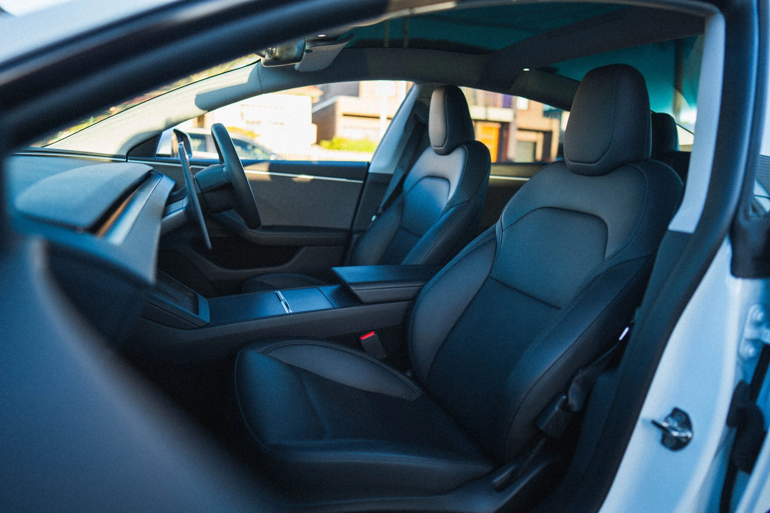 The interior of a modern electric vehicle showing front and rear seats, dashboard, and steering wheel.