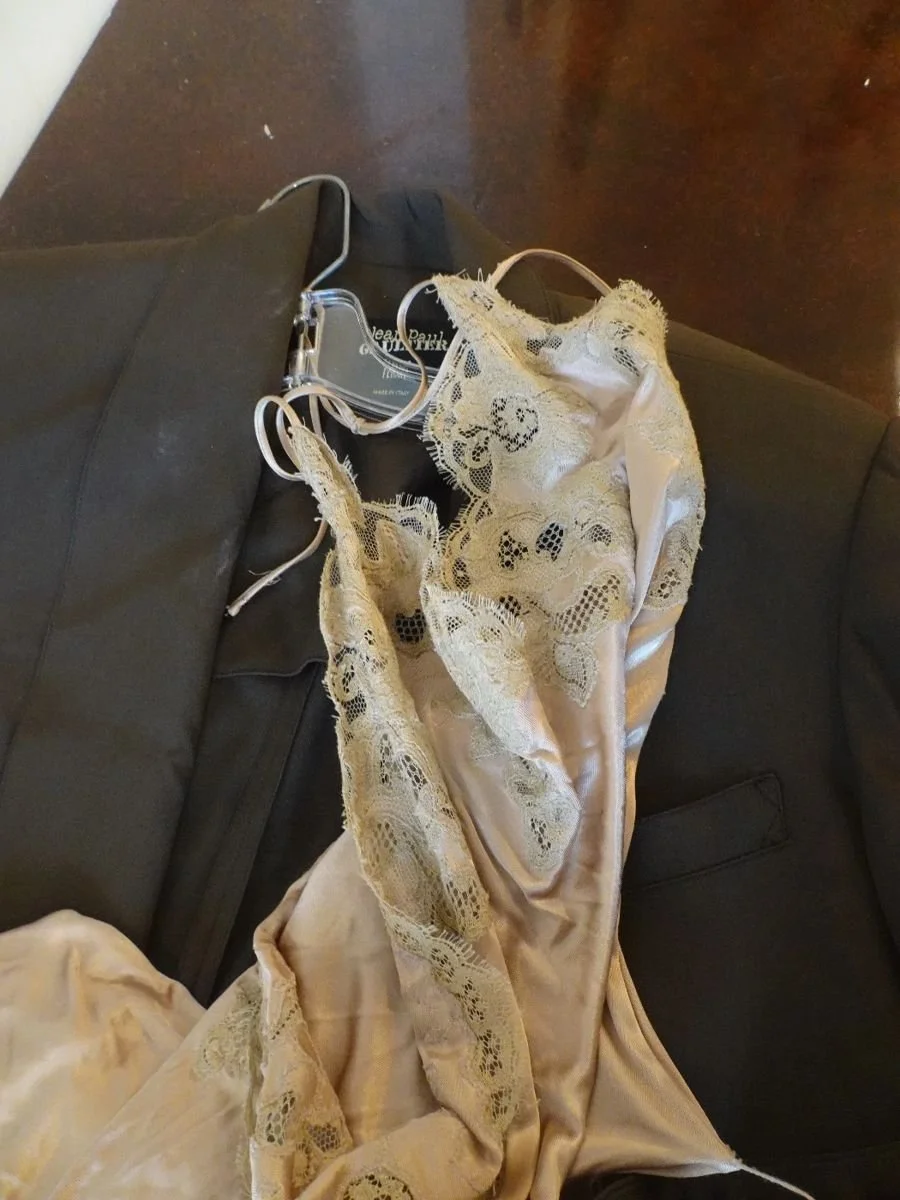 A beige satin dress with lace details draped over a black sofa.
