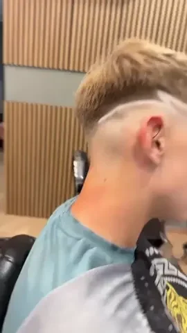 Close-up of a young man with a short haircut, sitting in a barber shop.