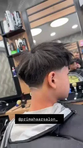 Side profile of a young boy with a fresh haircut inside a hair salon.